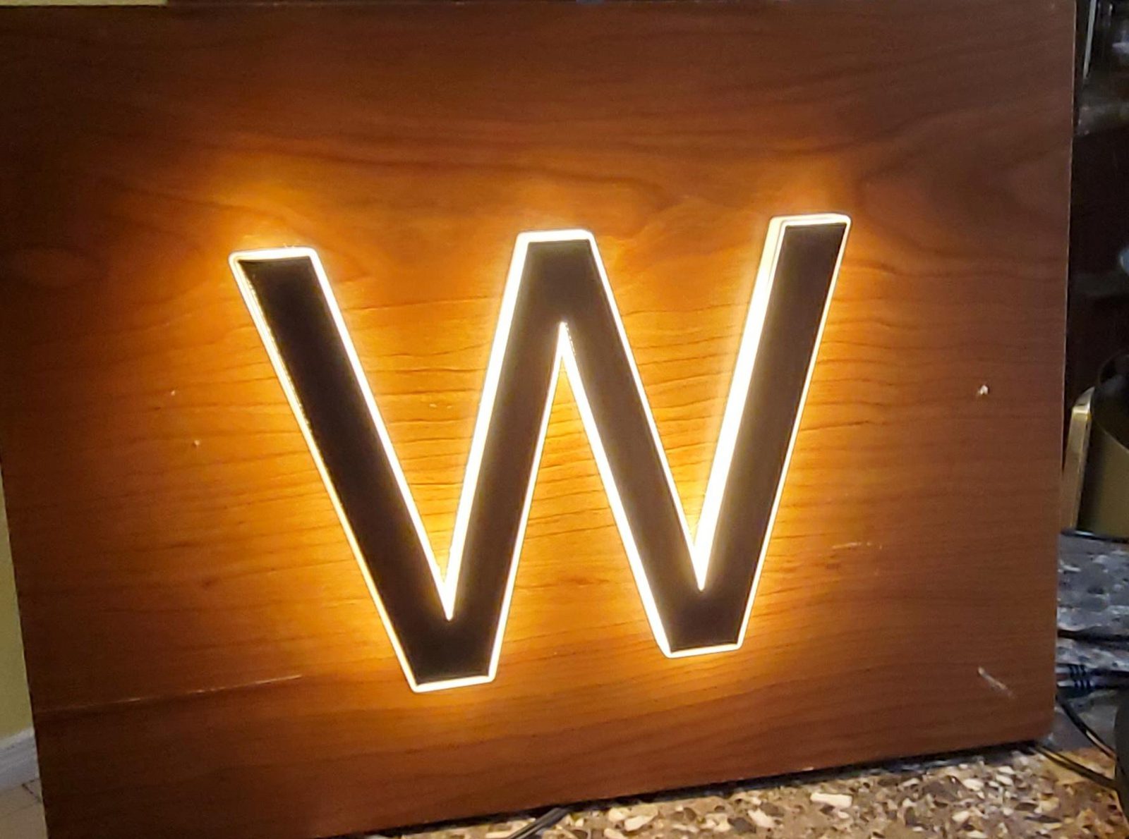 Laser-cut glowing letter W sign on wood