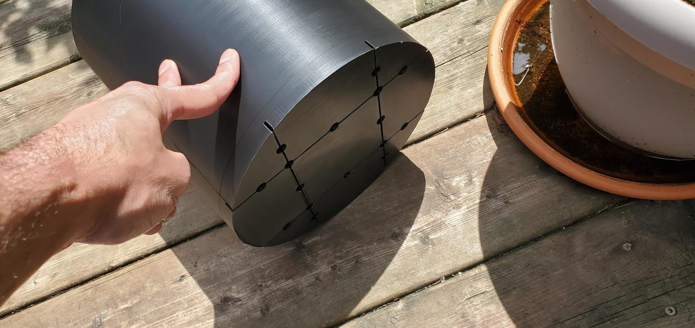 Black 3D-printed curved plant pot held in hand